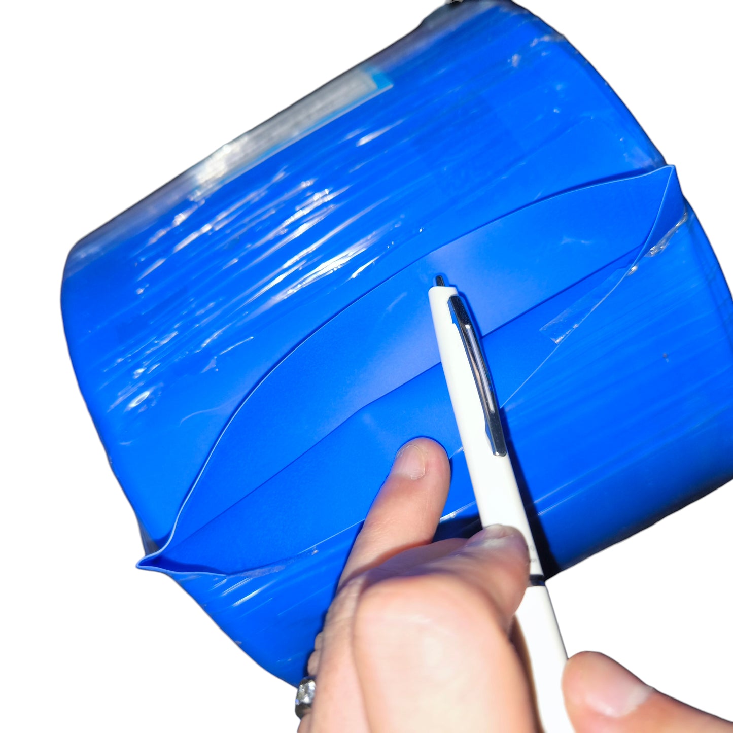 Hand using a white pen to cut blue tape on a white background