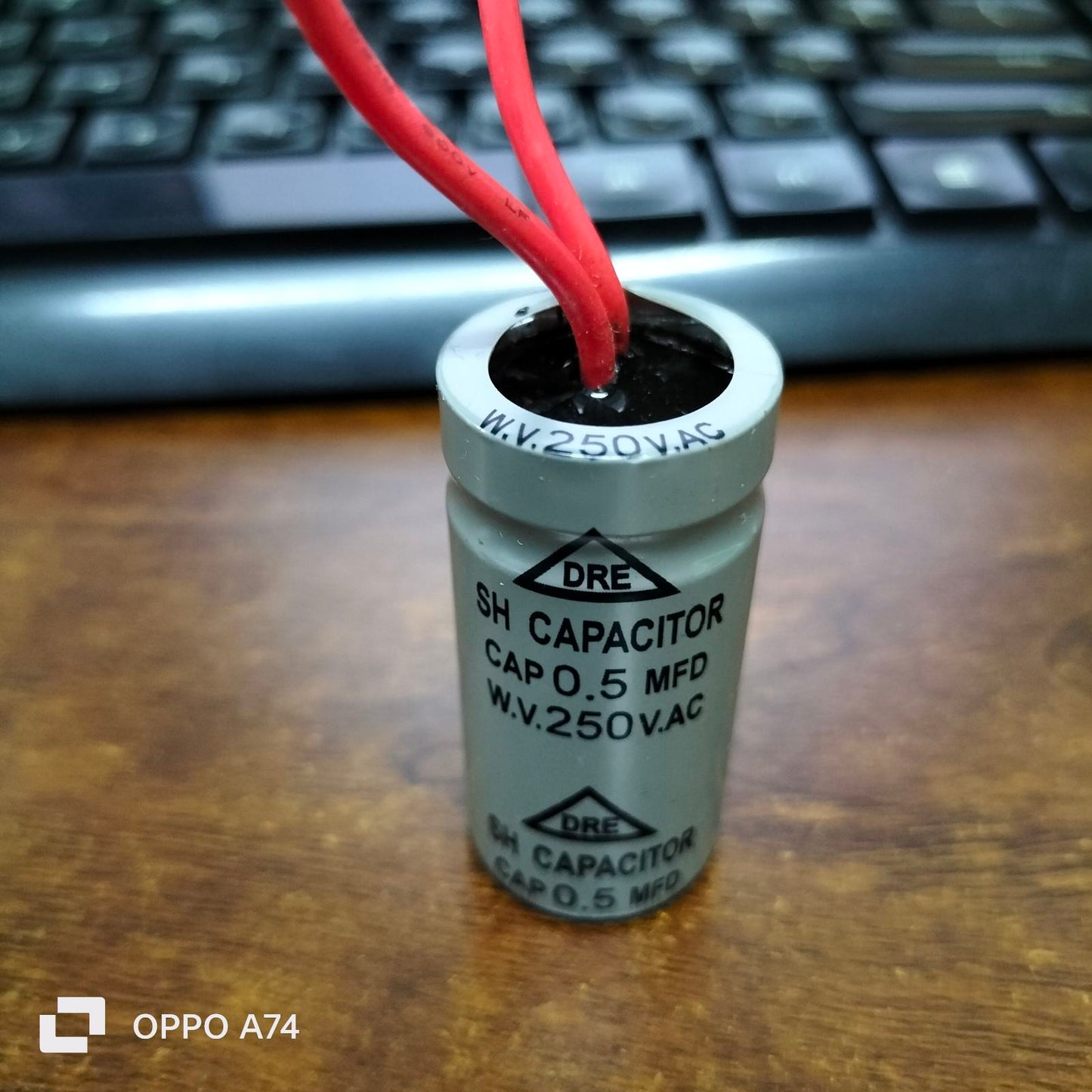 DRE 250 VAC Motor Running Capacitor with red wires and a silver cylindrical body