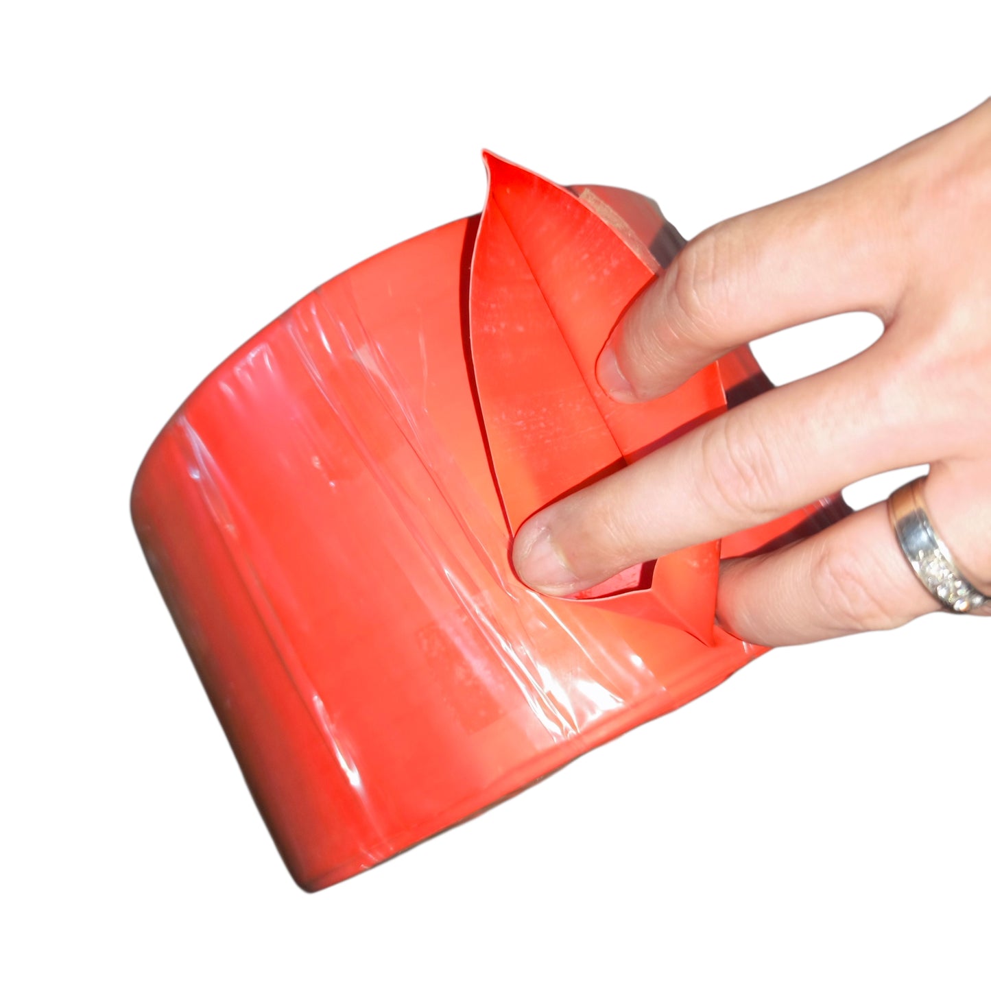 Hand holding a red plastic tool against a white background
