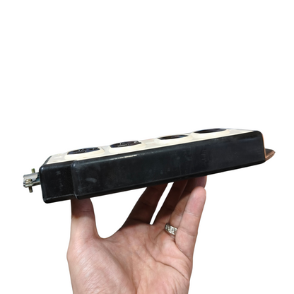 Hand holding a black electronic device with multiple sockets on a white background