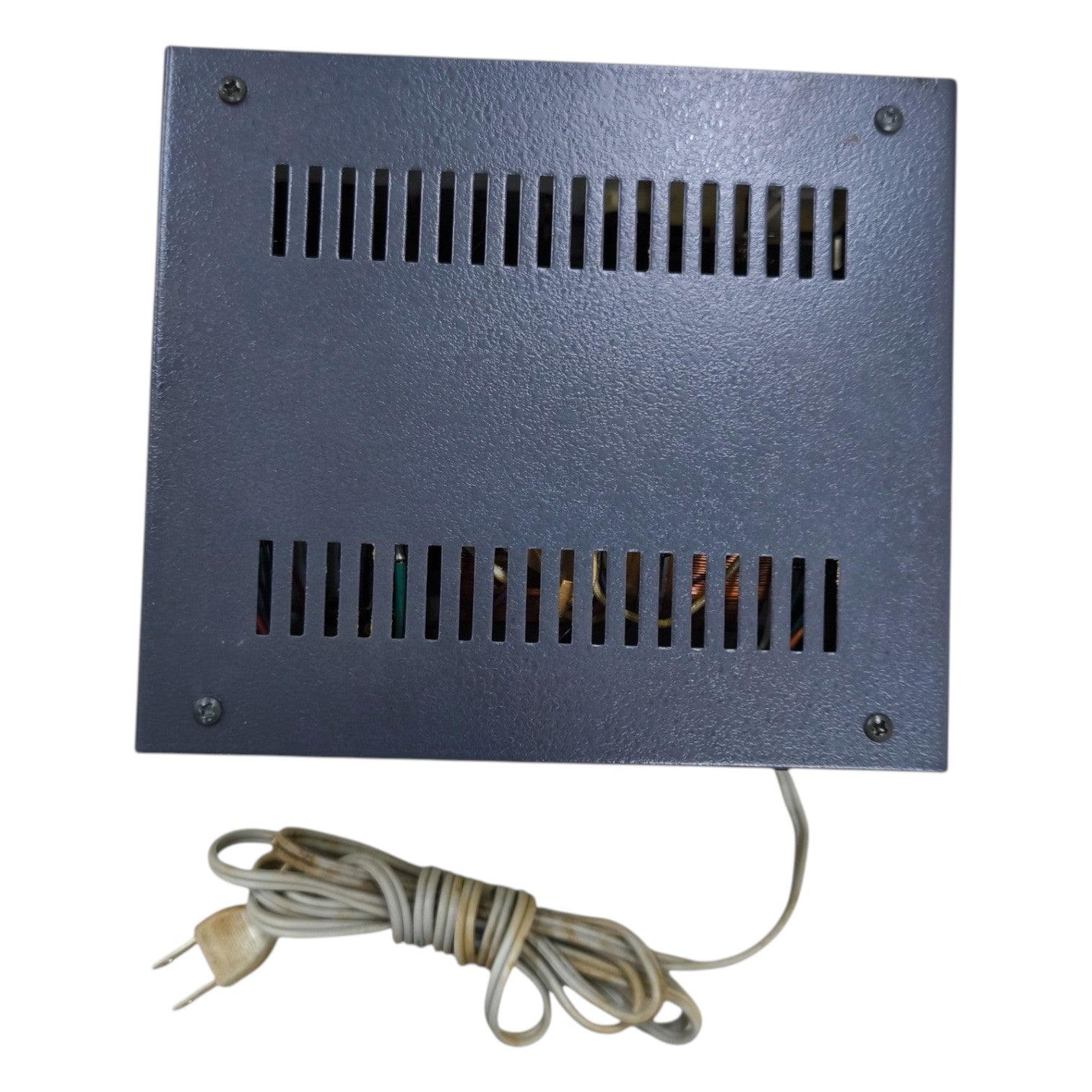 Rectangular metal device with ventilation grilles and a power cord on a white background