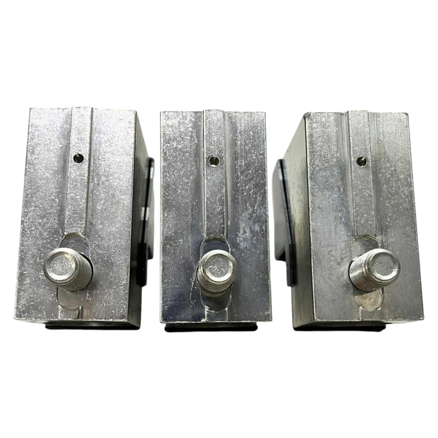 Three metallic blocks with cylindrical components on a white background