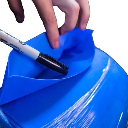 Hand holding a marker over a blue surface with a white background