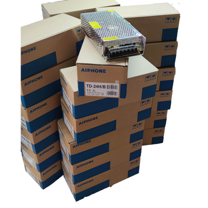 Aiphone 24 station intercom system components stacked in labeled boxes with a metal power supply unit on top
