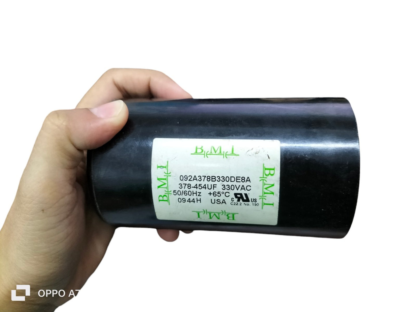 BMI starting capacitor 378-454UF black cylindrical electrical component held in hand