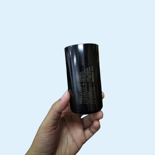 Mallory Motor Capacitor 270-324uF 220V held in hand with a sleek black design for electrical applications
