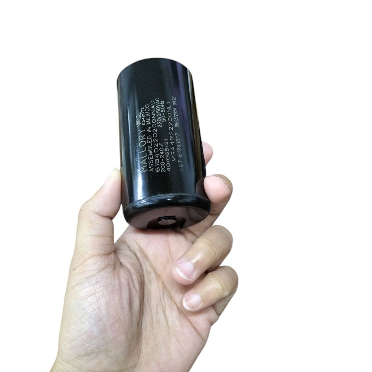 Mallory black motor capacitor held in hand for electrical circuitry and parts