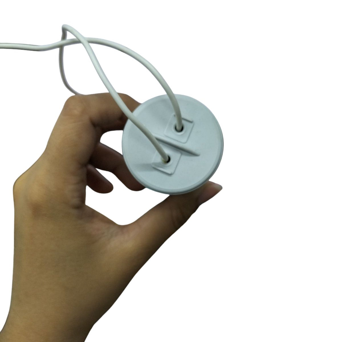 Hand holding a Syscap Motor Capacitor with two protruding wires for electrical applications