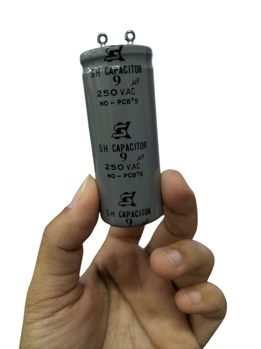 SH Motor Run Capacitor 9UF 250 VAC held between fingers for electrical circuitry use