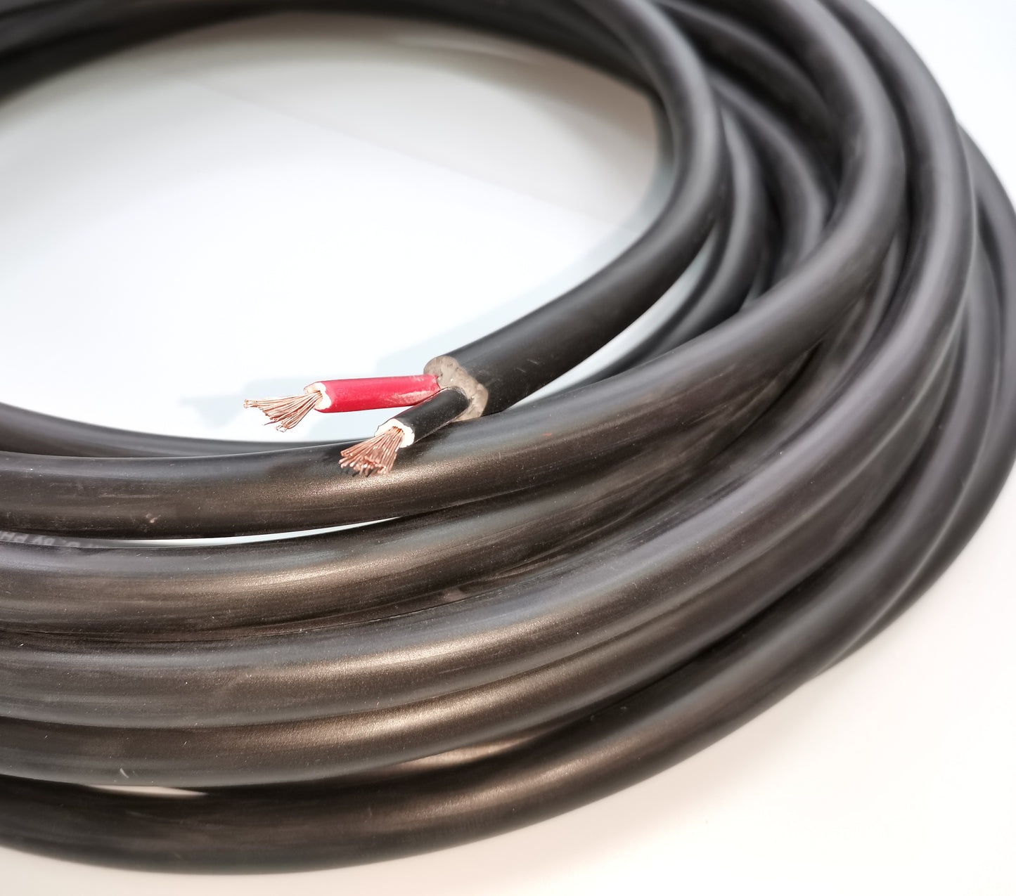 Coiled black Phelps Dodge perma cord wire with exposed copper ends for electrical connections