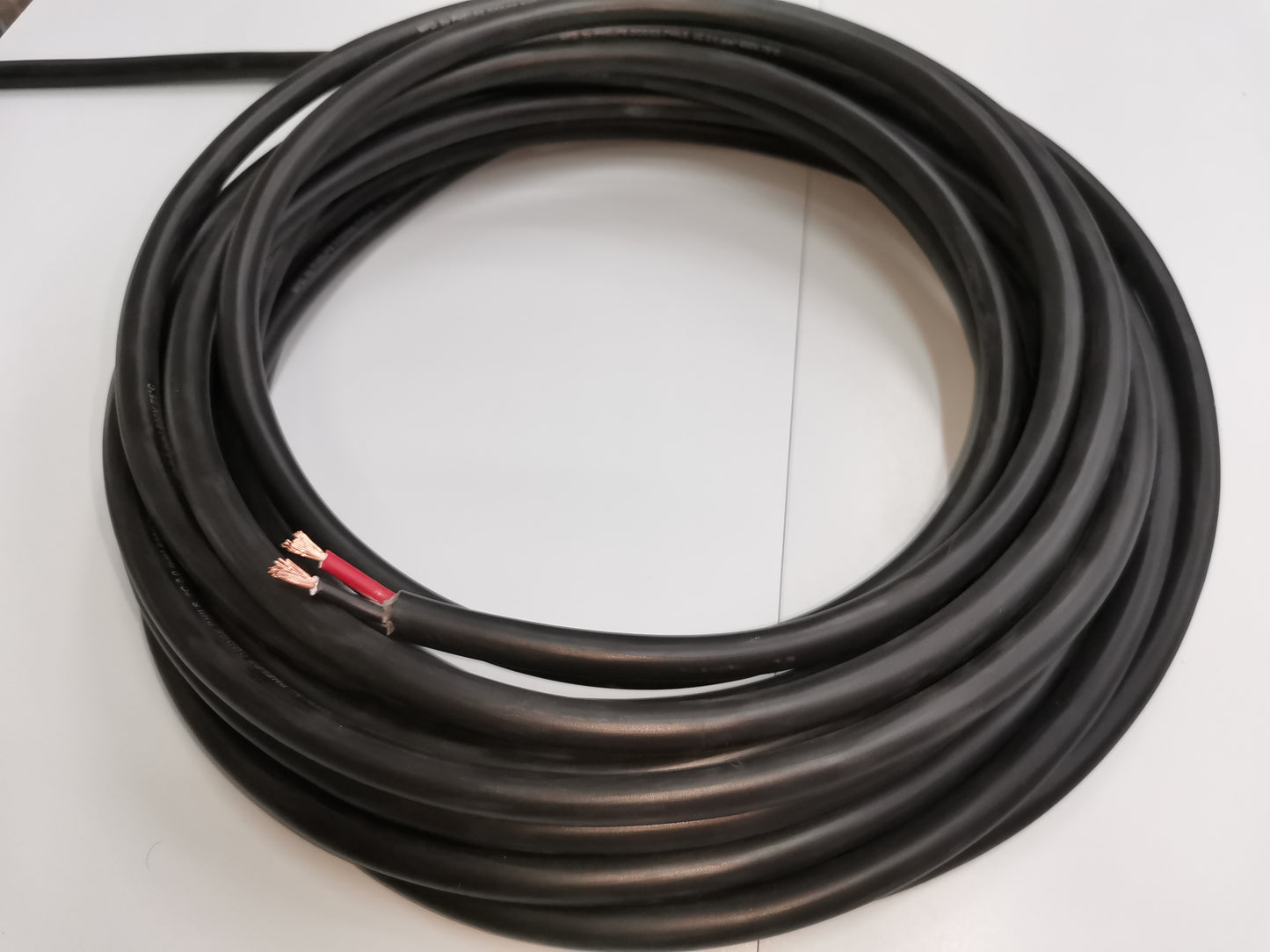 Coiled Phelps Dodge perma cord wire with black insulation and exposed copper ends