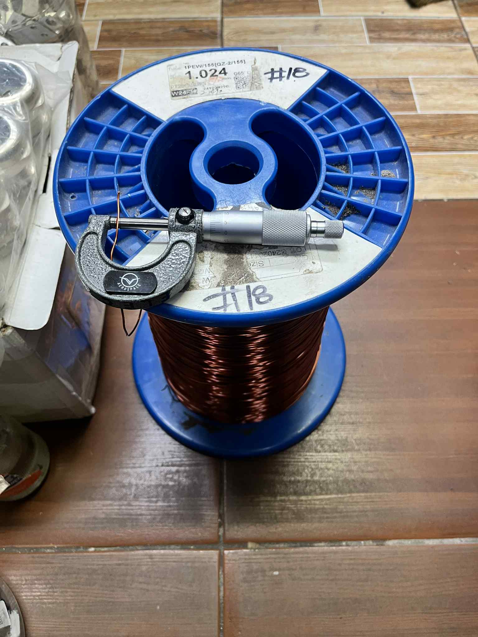 Philflex Magnet Wire AWG 18 600G on a blue spool with a micrometer for measuring wire thickness