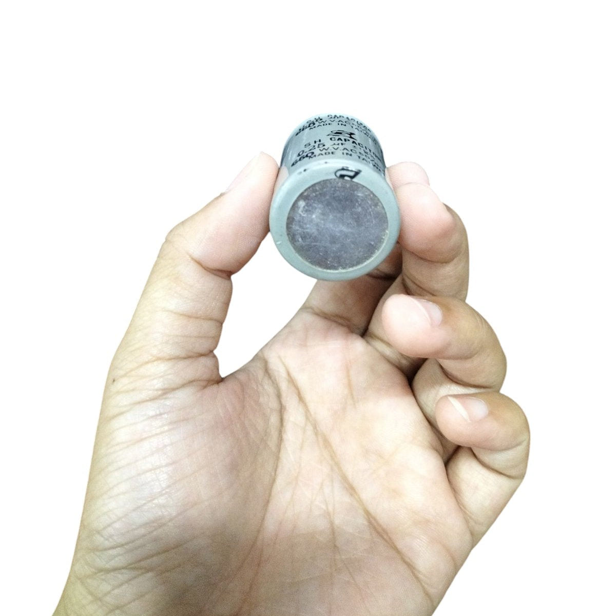 Hand holding an SH running capacitor for Motor, designed for electrical efficiency and performance