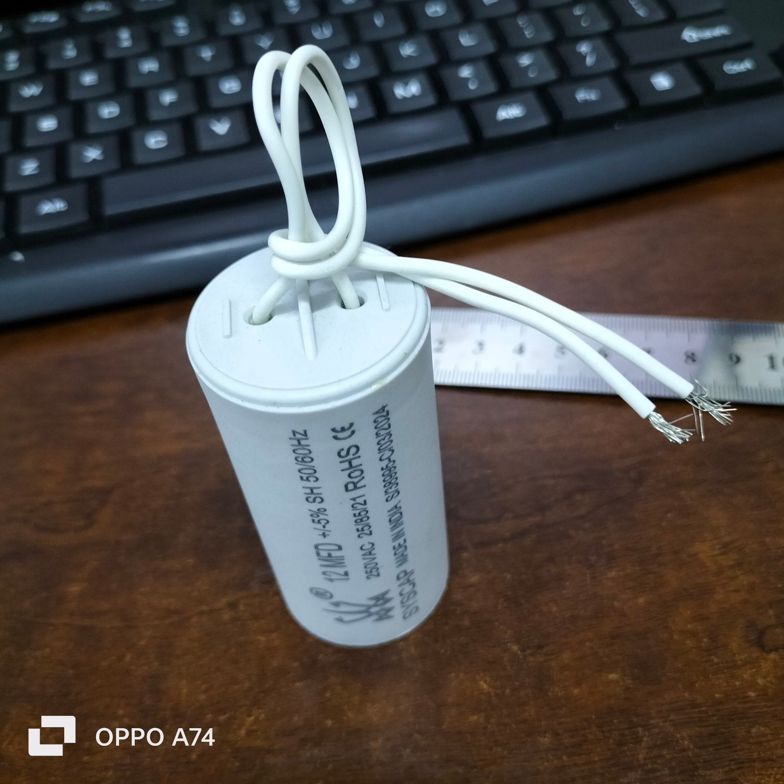 Syscap 12MFD 250 VAC Running Capacitor with white wires on wooden surface near keyboard and ruler