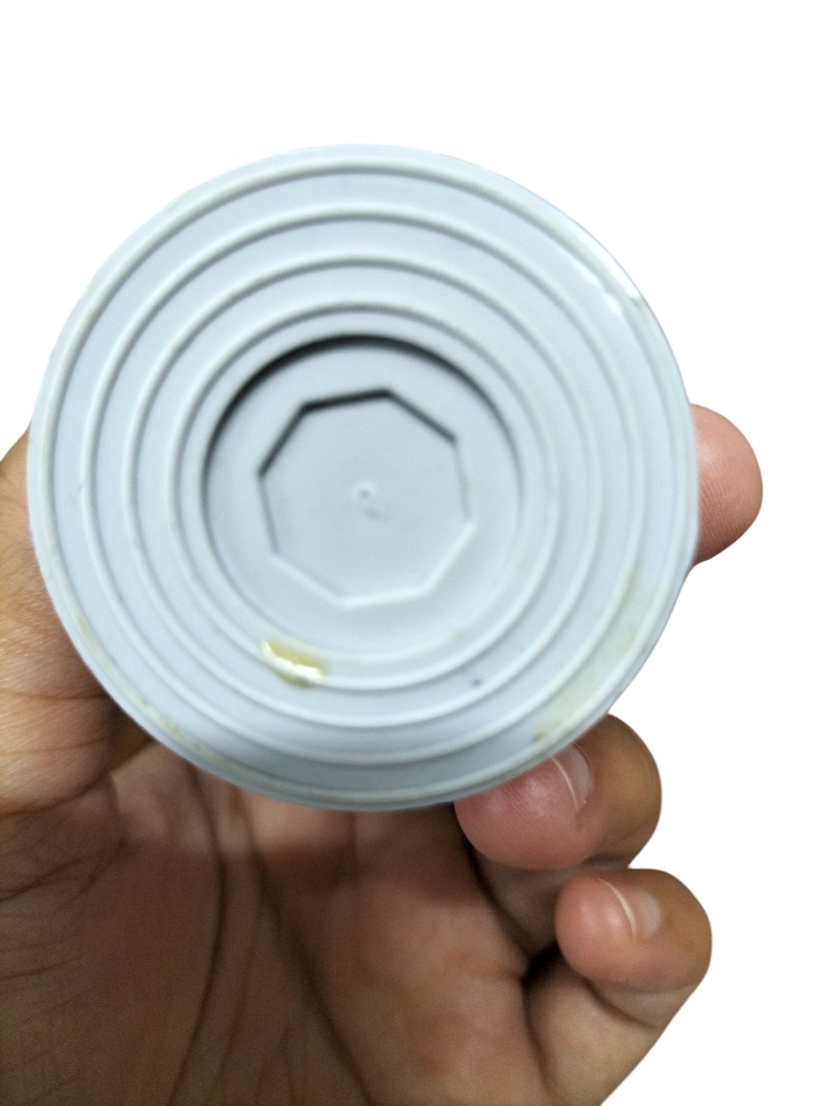 Hand holding a 16MFD Motor Running Capacitor with a round, flat top for electrical applications