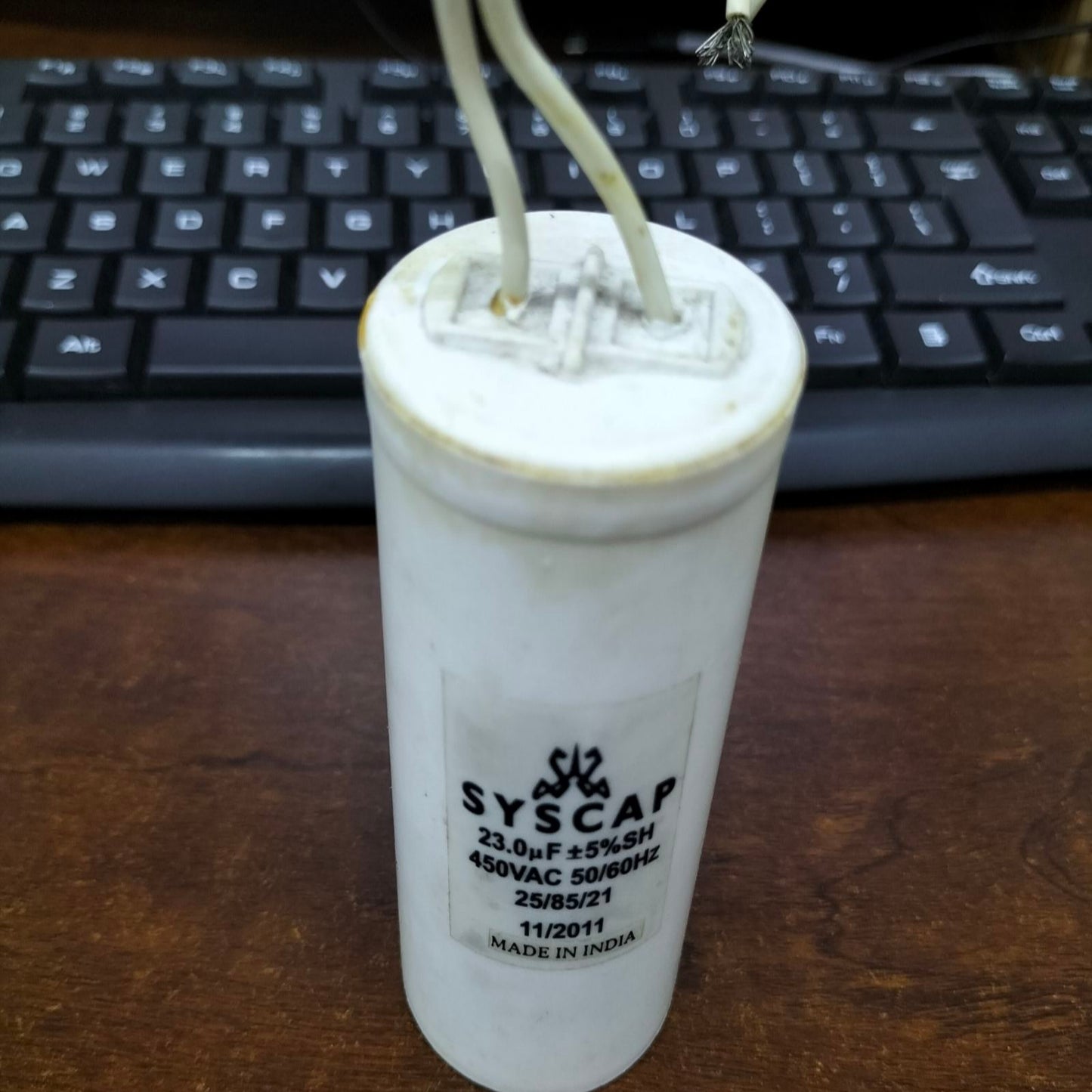 Syscap 23MFD 450VAC motor capacitor white cylindrical electrical component with wires