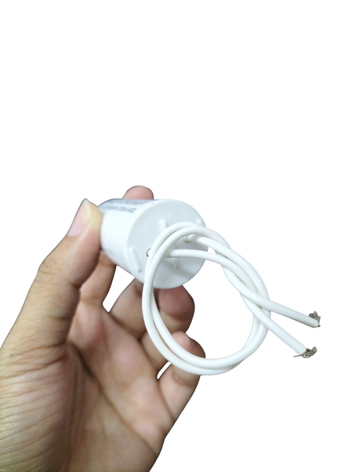 Syscap 250V AC motor running capacitor held in hand with white wires attached for electrical applications