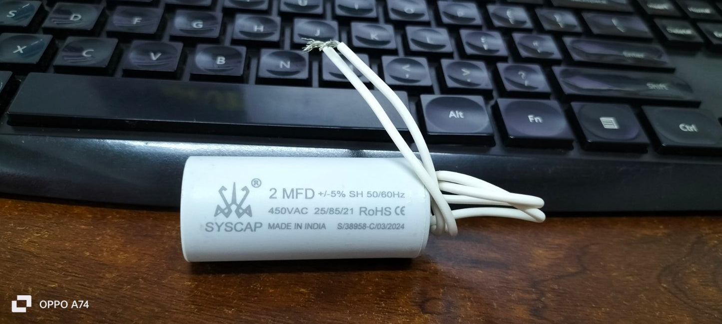 Syscap 2MFD 450V AC Running Capacitor electrical component with white wires on a wooden surface