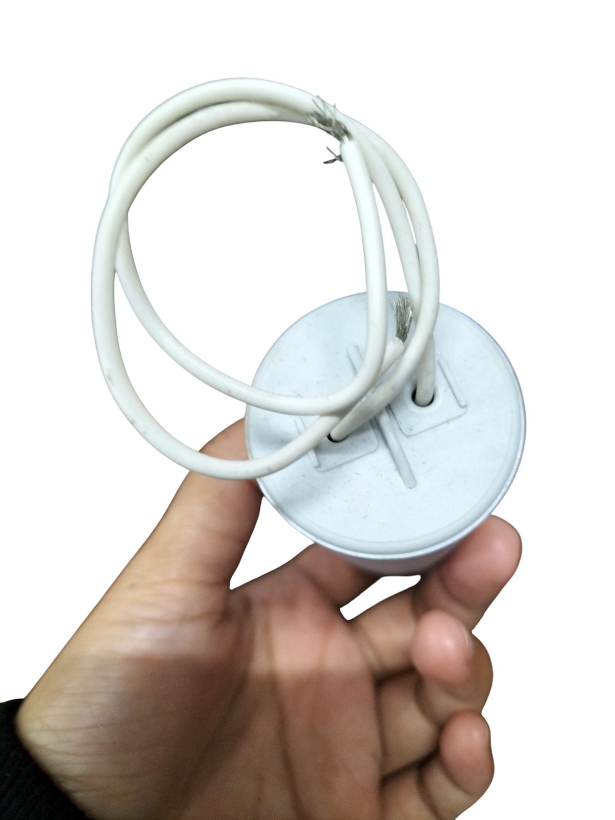 Hand holding a Syscap 30uF 600V motor running capacitor with connecting wires for electrical applications