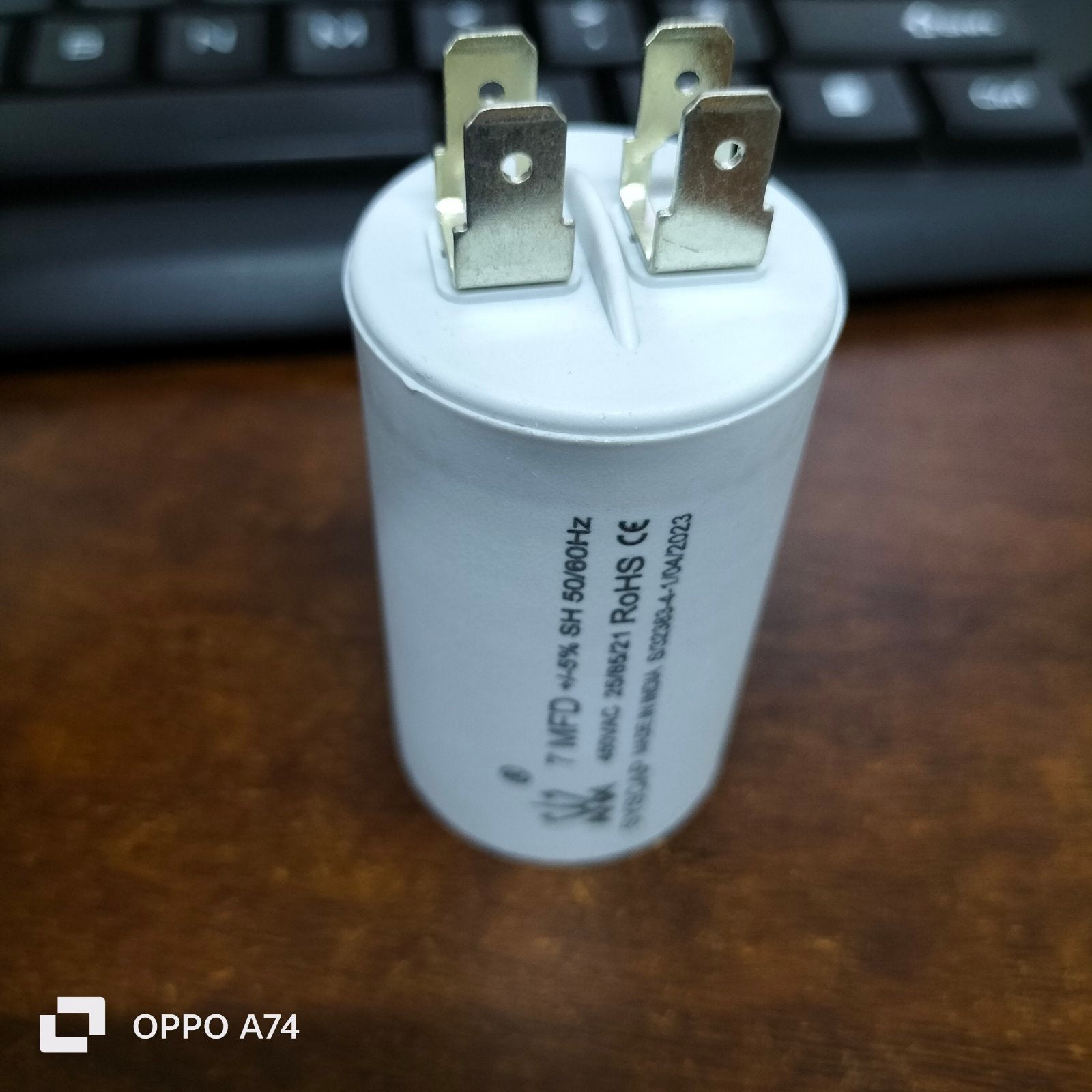 Syscap 7MFD 450Vac Run Capacitor electrical component with metal terminals on wooden surface