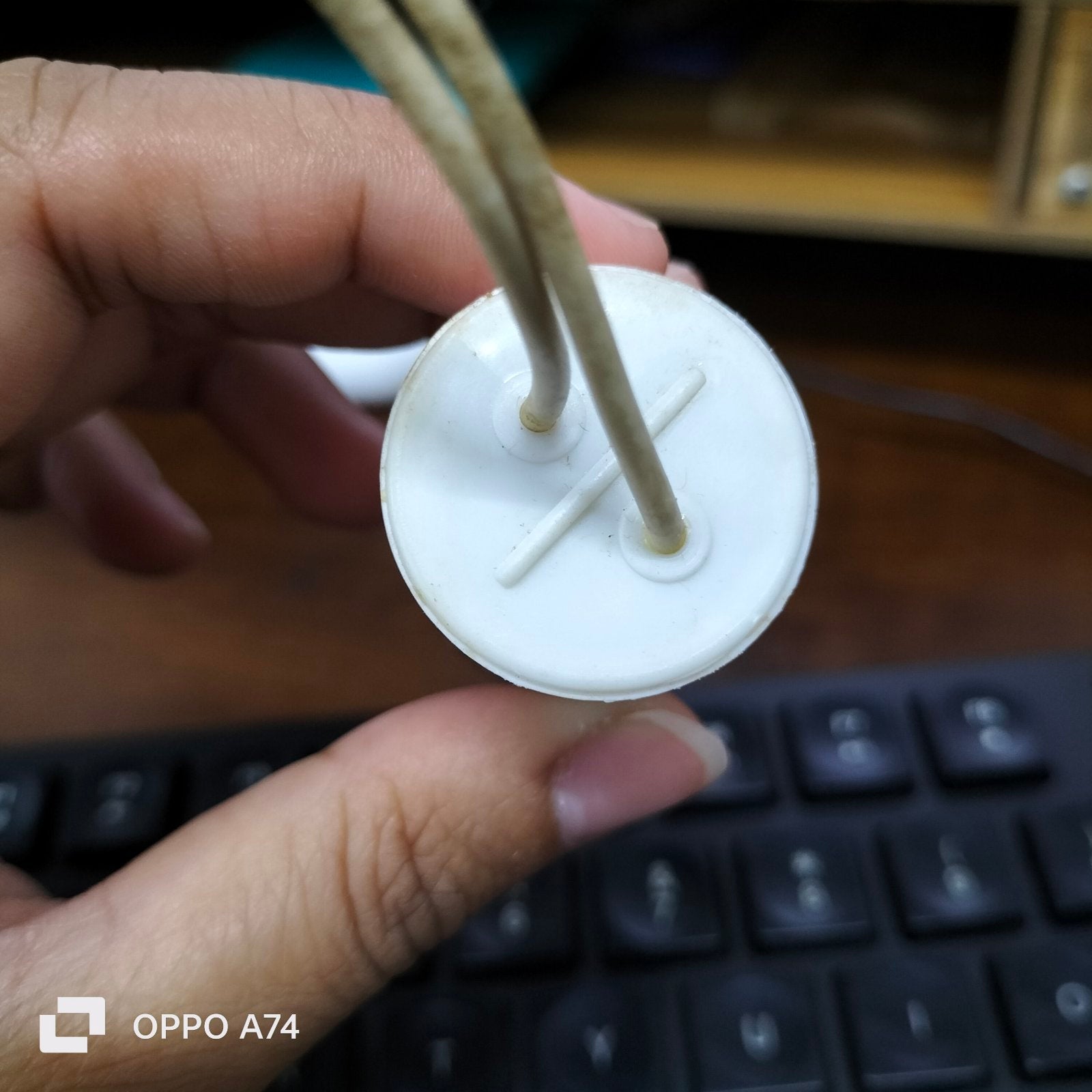 Hand holding a white apacitor 350V AC Electrical Part with two connecting wires