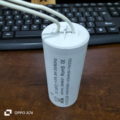 Syscap industrial motor capacitors white cylindrical electrical component with wires on wooden surface