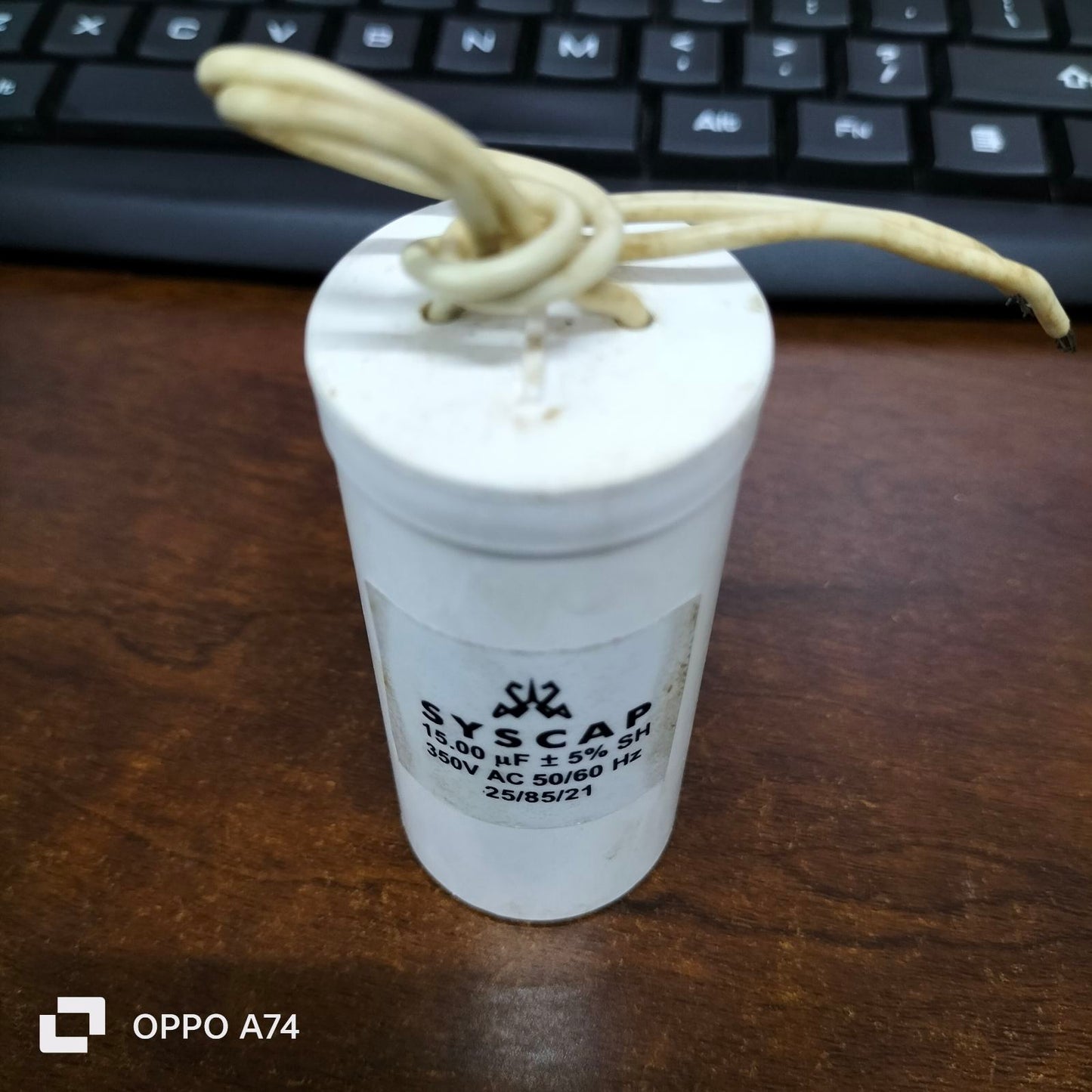 Syscap motor running capacitor 15mfd white cylindrical electrical component with wires on keyboard background