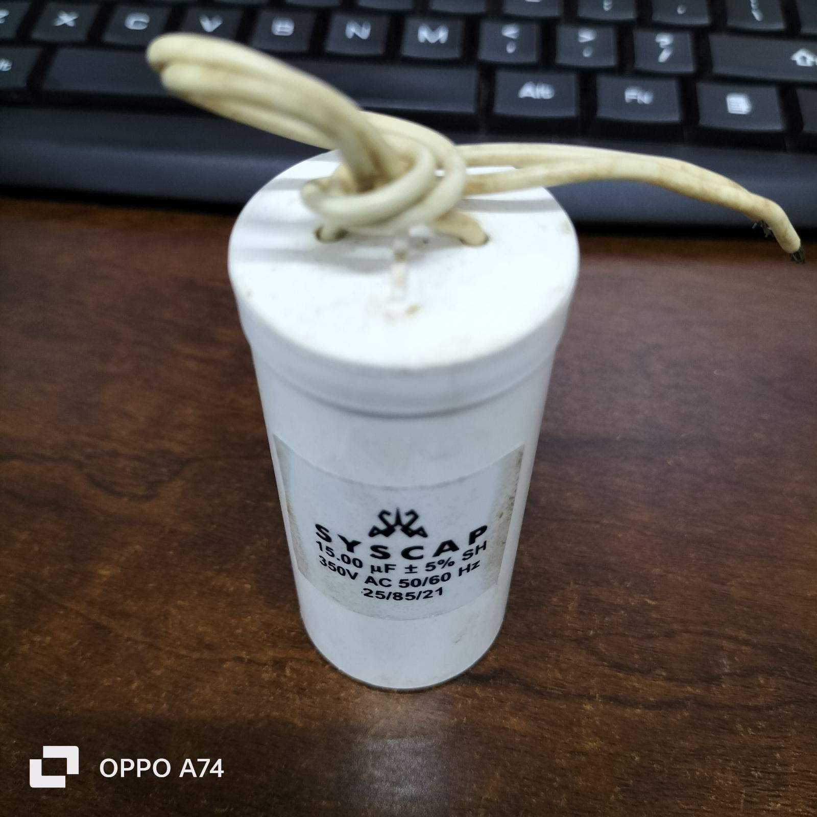 Syscap motor running capacitor 15mfd white cylindrical electrical component with wires on keyboard background