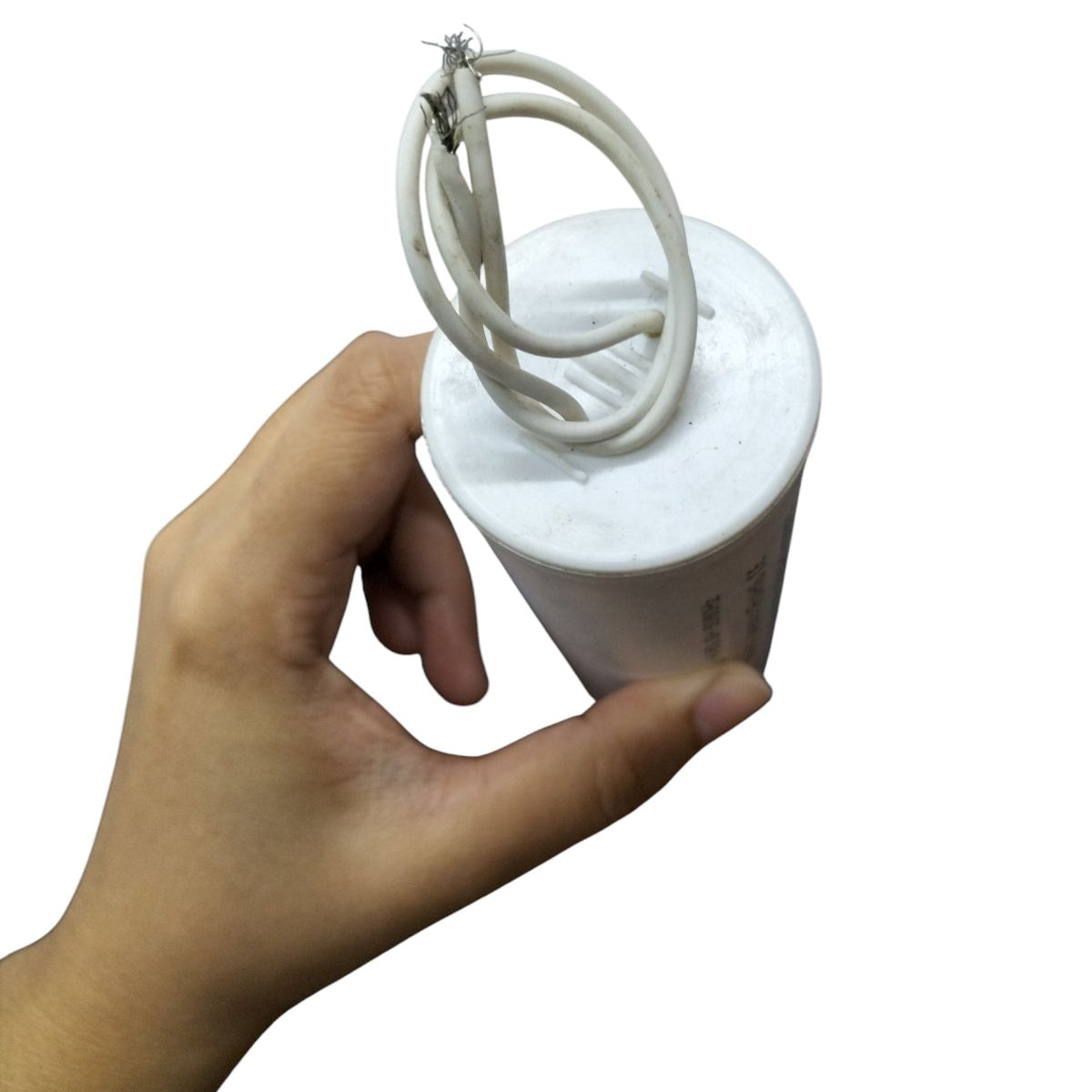 Hand holding a motor running capacitor 25uF 600V with attached wires for electrical applications