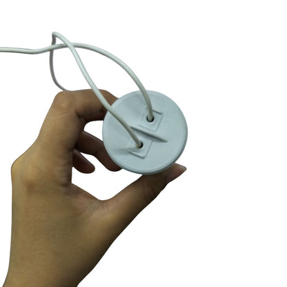 Hand holding a white motor running capacitor with attached wires for electrical circuitry parts