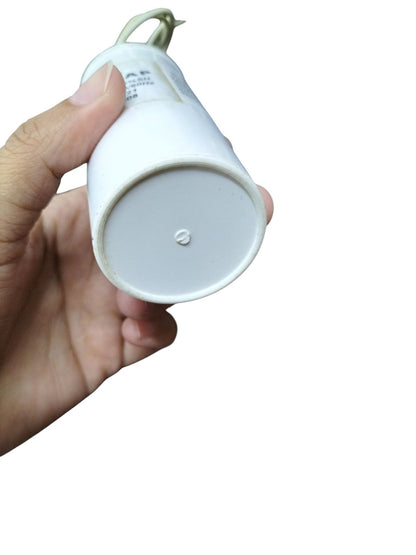 Hand holding a Syscap Running Capacitor 15uF 600V with a white casing and wire connection