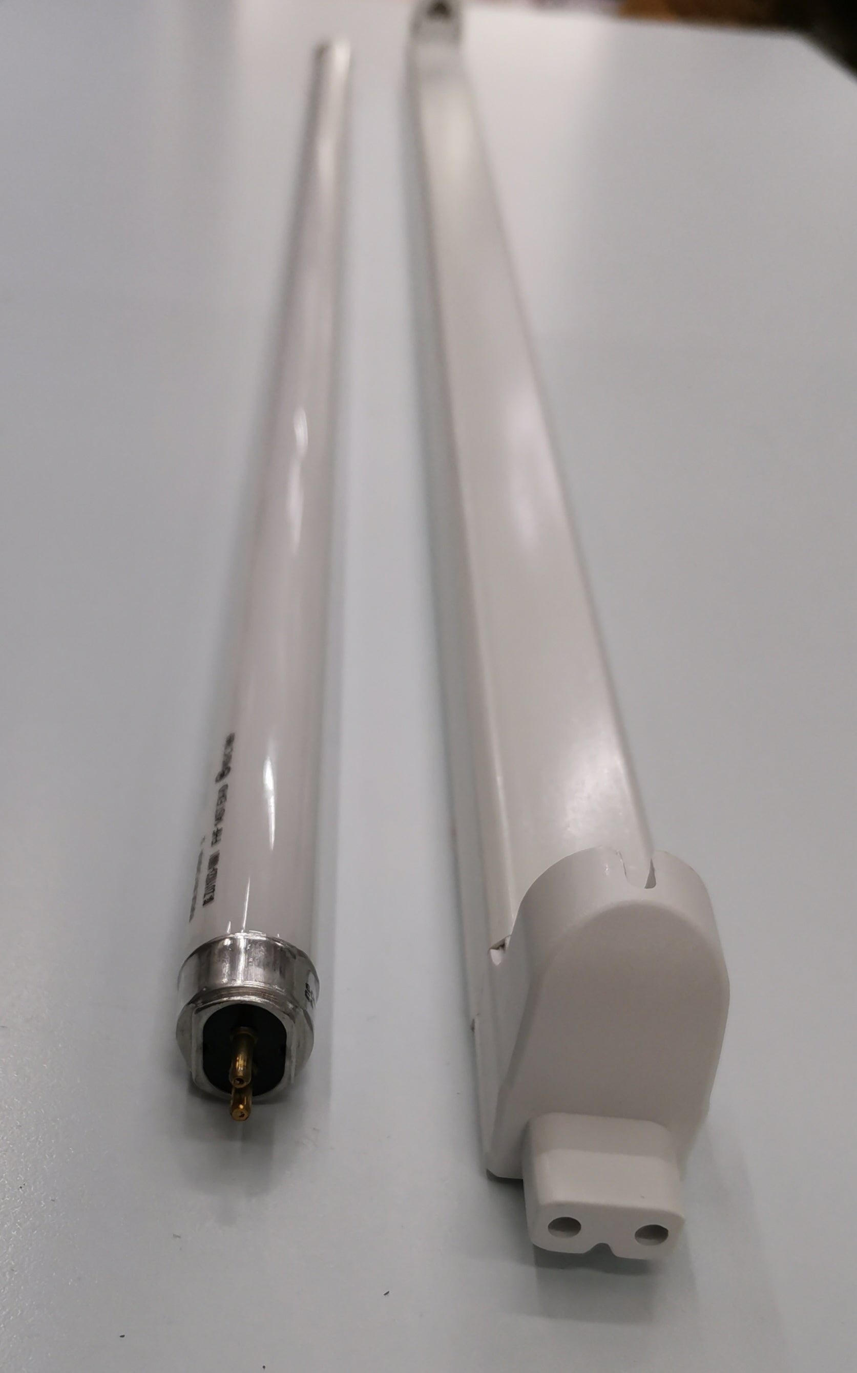 Philips T5 Fluorescent Lamp 28 Watts Daylight tube next to a white fluorescent fixture on a white surface
